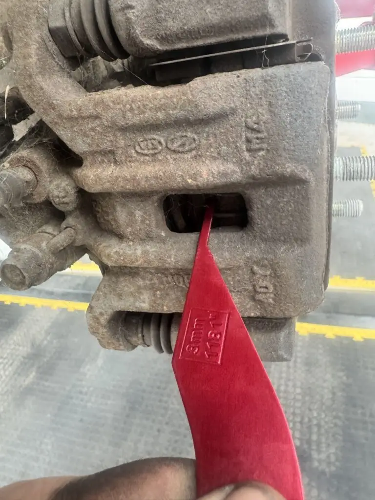 Checking brake pad thickness with a gauge during an inspection at our Royston workshop